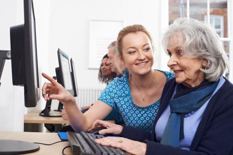 Librarian helping older woman on desktop