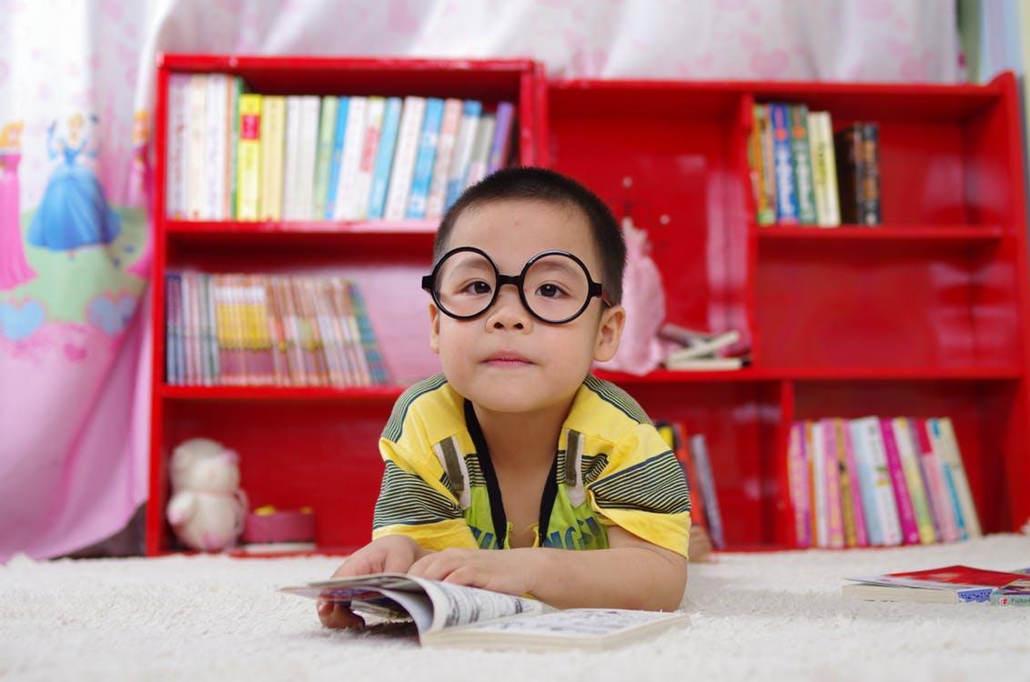 Young boy with glasses among bookshelves